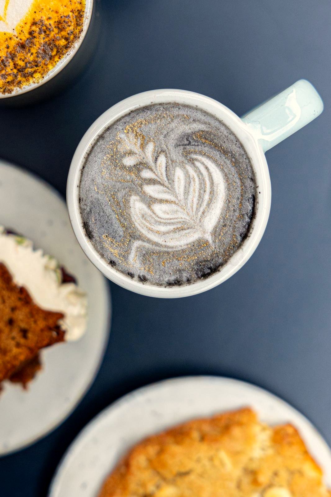 Une tasse de latte et son latte art vue du dessus, sur une table bleue chez Papilles
