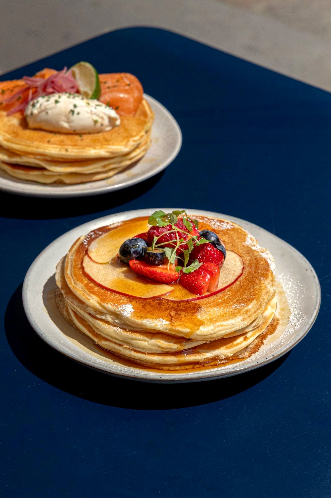 Pancakes aux fruits frais et pancakes au saumon sur une table bleue chez Papilles