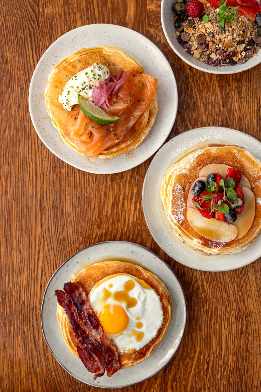 Pancakes au saumon, aux fruits et au bacon sur une table en bois chez Papilles
