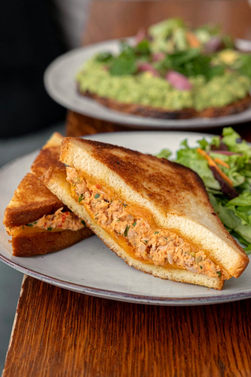 Tuna melt au cheddar fondu coupé en deux, servi avec du mesclun chez Papilles
